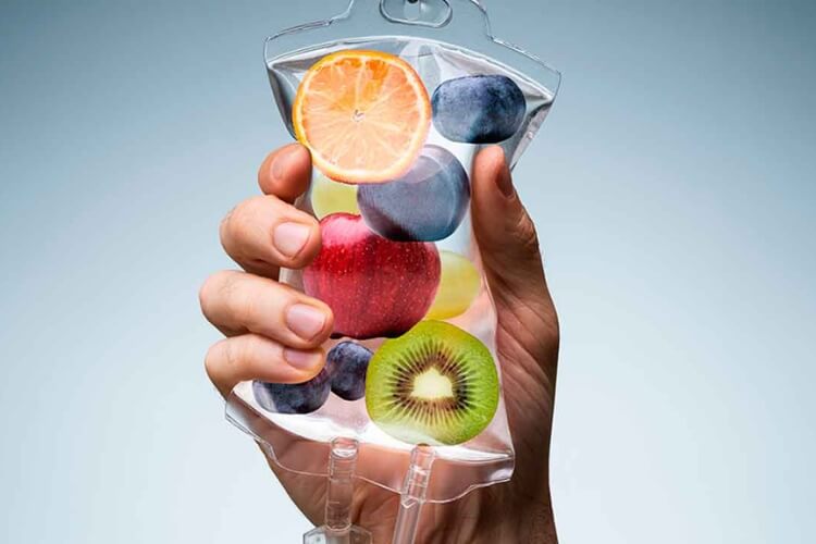 Uma mão segurando uma bolsa de soro com frutas dentro